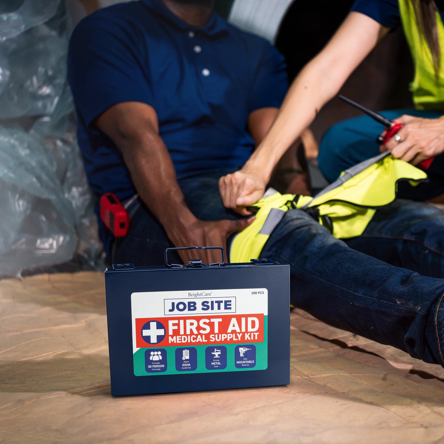 First Aid Kit for Job Site with person performing aid in the background